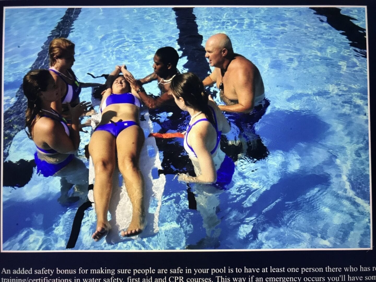 A group of people in the pool with one woman laying on her stomach.