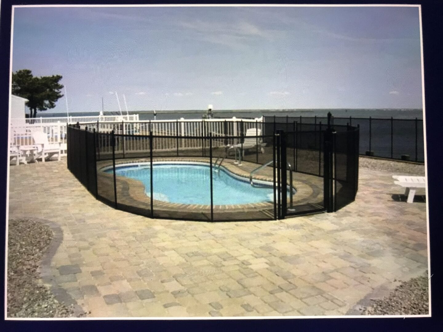 A pool with a fence around it and water in the background.