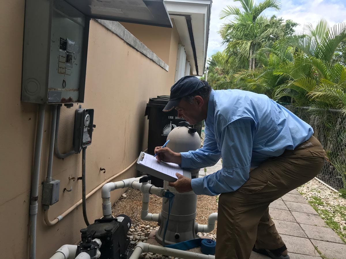 A man in blue shirt and brown pants working on pipes.