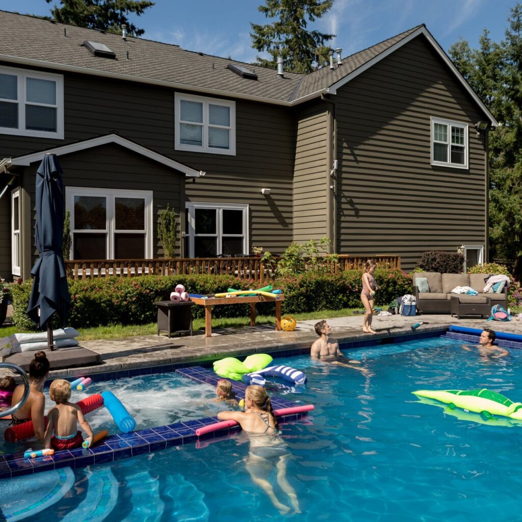 A group of people in the pool at a house.