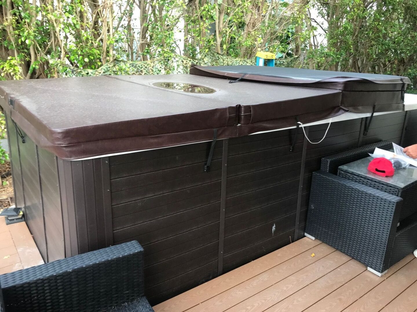 A hot tub with a wooden deck and trees in the background.