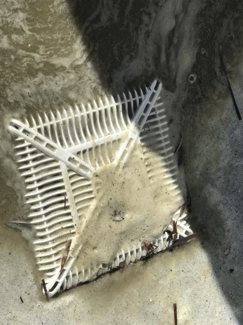 A square metal object sitting on top of concrete.