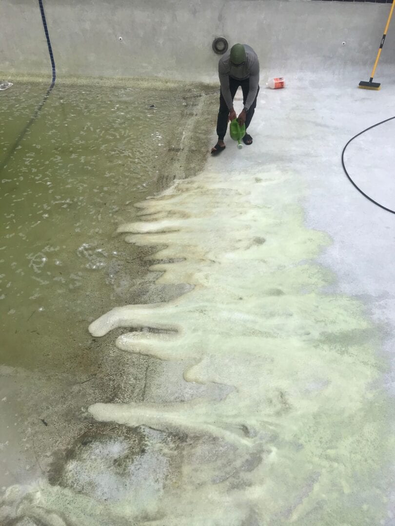 A person is cleaning the floor of an outdoor area.