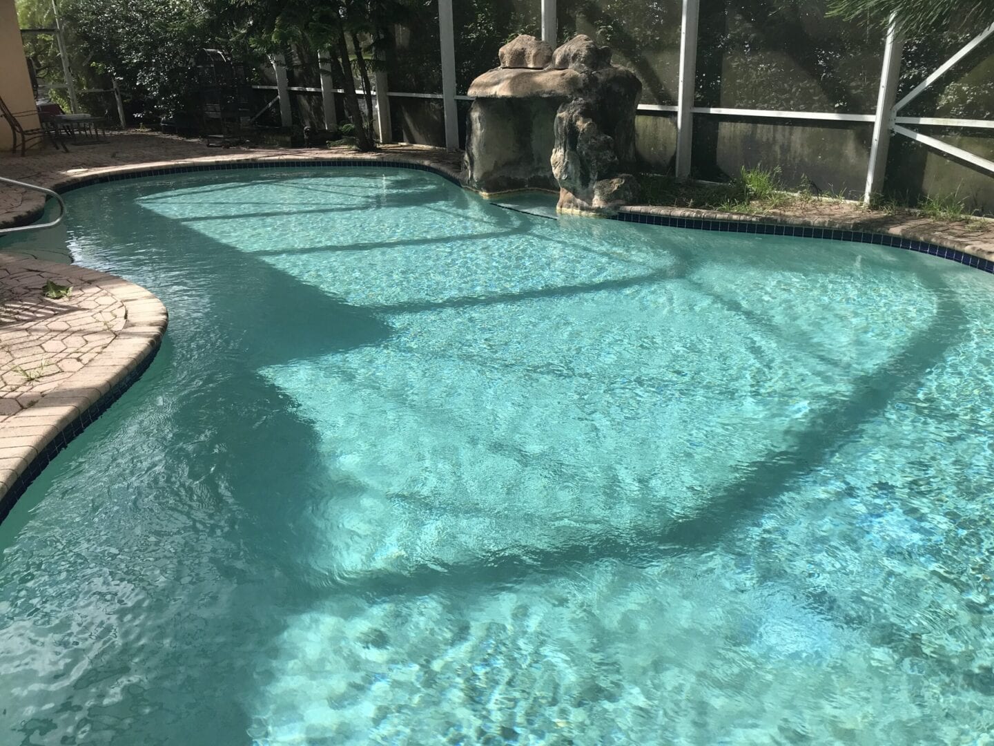 Curvy oval pool with stone structure feature on one side