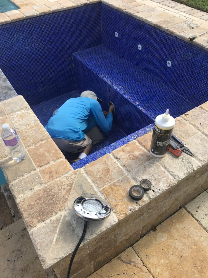 Man checking the pipes of an empty, small pool