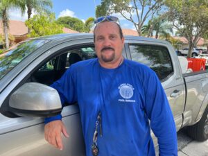 A man standing next to a silver car.